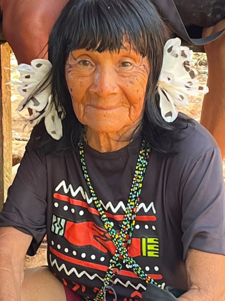 Portrait of a Yanomami elder wearing a Guardiãs do Bem Viver t-shirt and white feather ornaments