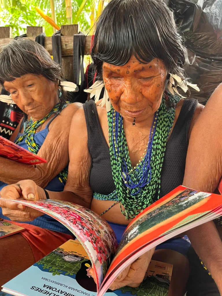 Two Yanomami elders reading printed materials from the AMYK association
